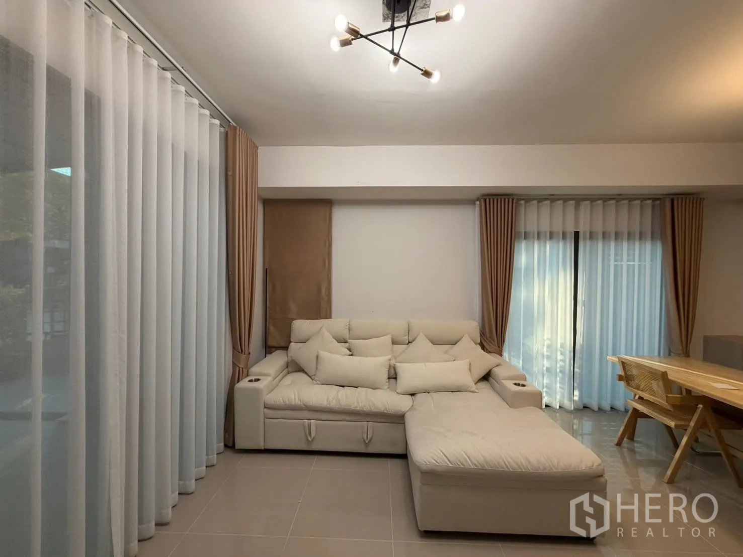 联排别墅 for rent in Bang Phli, Samut Prakan - 明亮客厅，L形沙发旁为两扇推拉落地门及长帘。