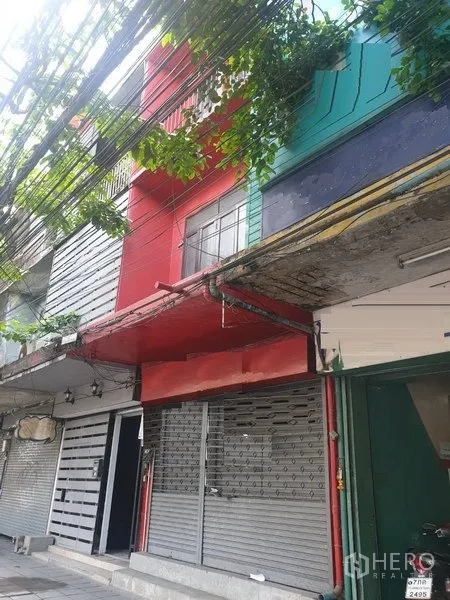 อาคารพาณิชย์ ให้เช่าในWatthana, Bangkok - ด้านหน้าตึกแถวสีแดงพร้อมประตูม้วนโลหะ ใกล้ BTS เอกมัย กรุงเทพฯ