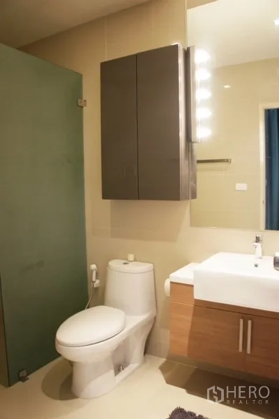 Condominium for rent in Phaya Thai, Bangkok - Second bathroom featuring vanity, wall cabinet, toilet and glass shower partition.