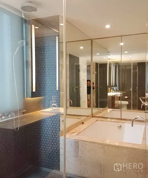 Condominium for sale in Pathum Wan, Bangkok - Spa-style bathroom featuring a large soaking tub, glass-enclosed shower and mirrored wall.