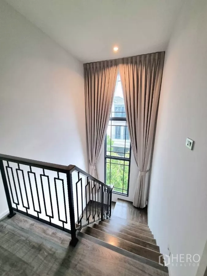 独立式住宅 出售在Prawet, Bangkok - 黑色金属栏杆楼梯，配高窗与窗帘。