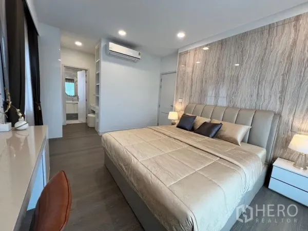 Detached House for rent or sale in Saphan Sung, Bangkok - Bright bedroom with ensuite access, air conditioning and a textured feature wall.
