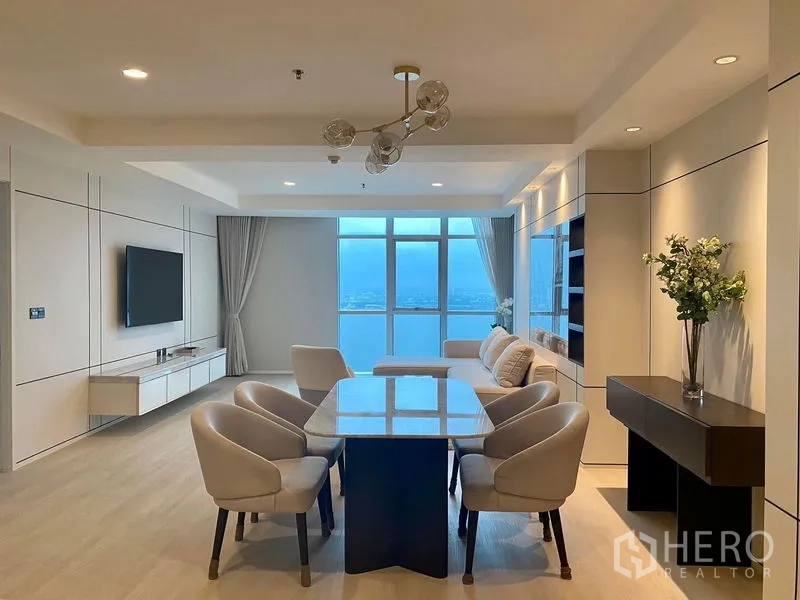 Condominium for rent in Khlong Luang, Pathum Thani - Bright living and dining area with six-seat table, sofa set and wide city-view windows.