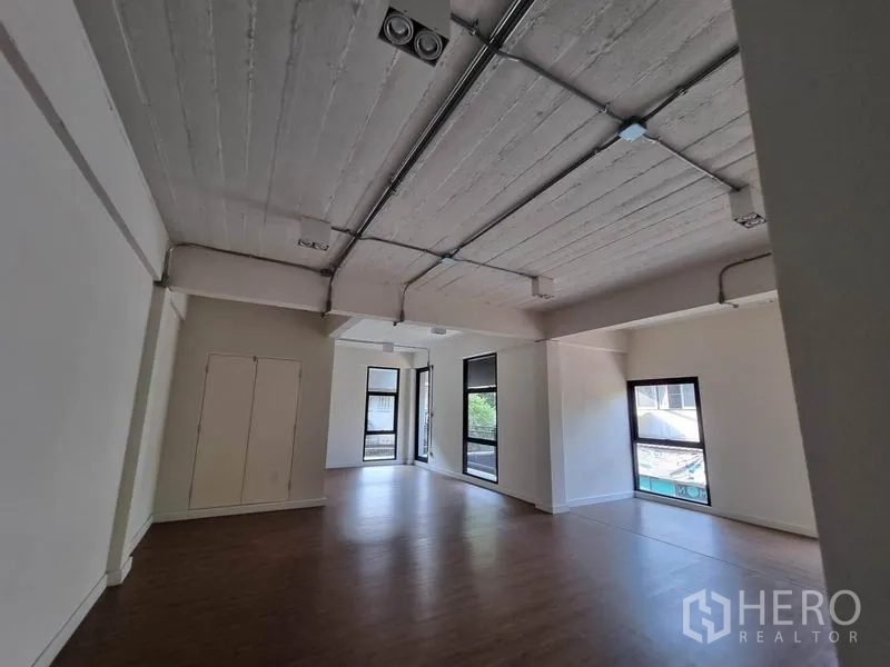 Home Office for rent or sale in Phaya Thai, Bangkok - Open workspace with exposed concrete ceiling, surface-mounted conduits and several windows.
