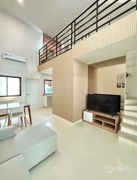 Townhouse for rent in Bang Phli, Samut Prakan - TV corner under the mezzanine with black railing and stairs.