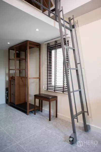 Detached House for rent in Phra Khanong, Bangkok - Metal ladder leading to a mezzanine loft beside a window with blinds and an open wood wardrobe.