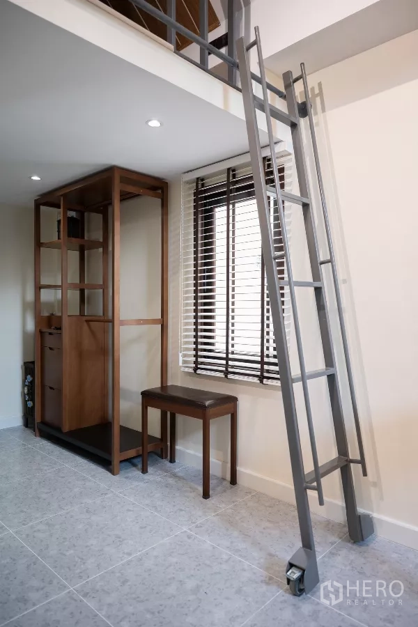 Detached House for rent in Phra Khanong, Bangkok - Metal ladder leading to a mezzanine loft beside a window with blinds and an open wood wardrobe.