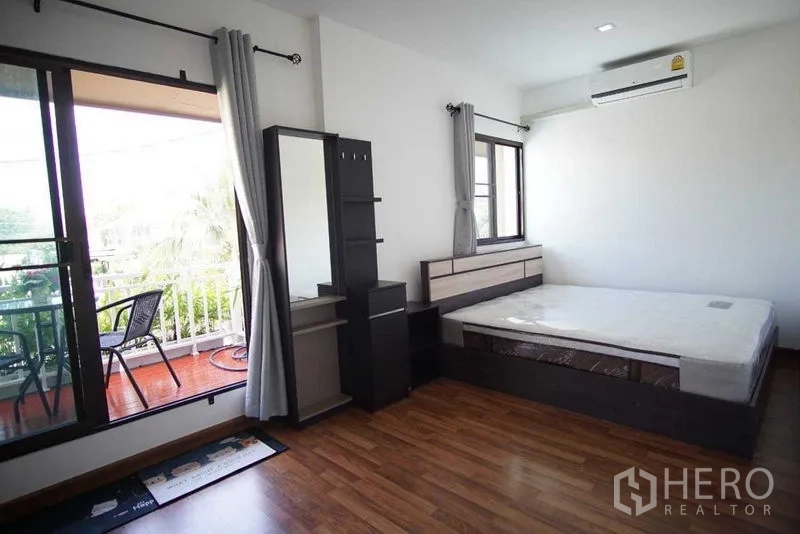 Townhouse for rent in Suan Luang, Bangkok - Primary bedroom with wood floors, balcony access and large windows.