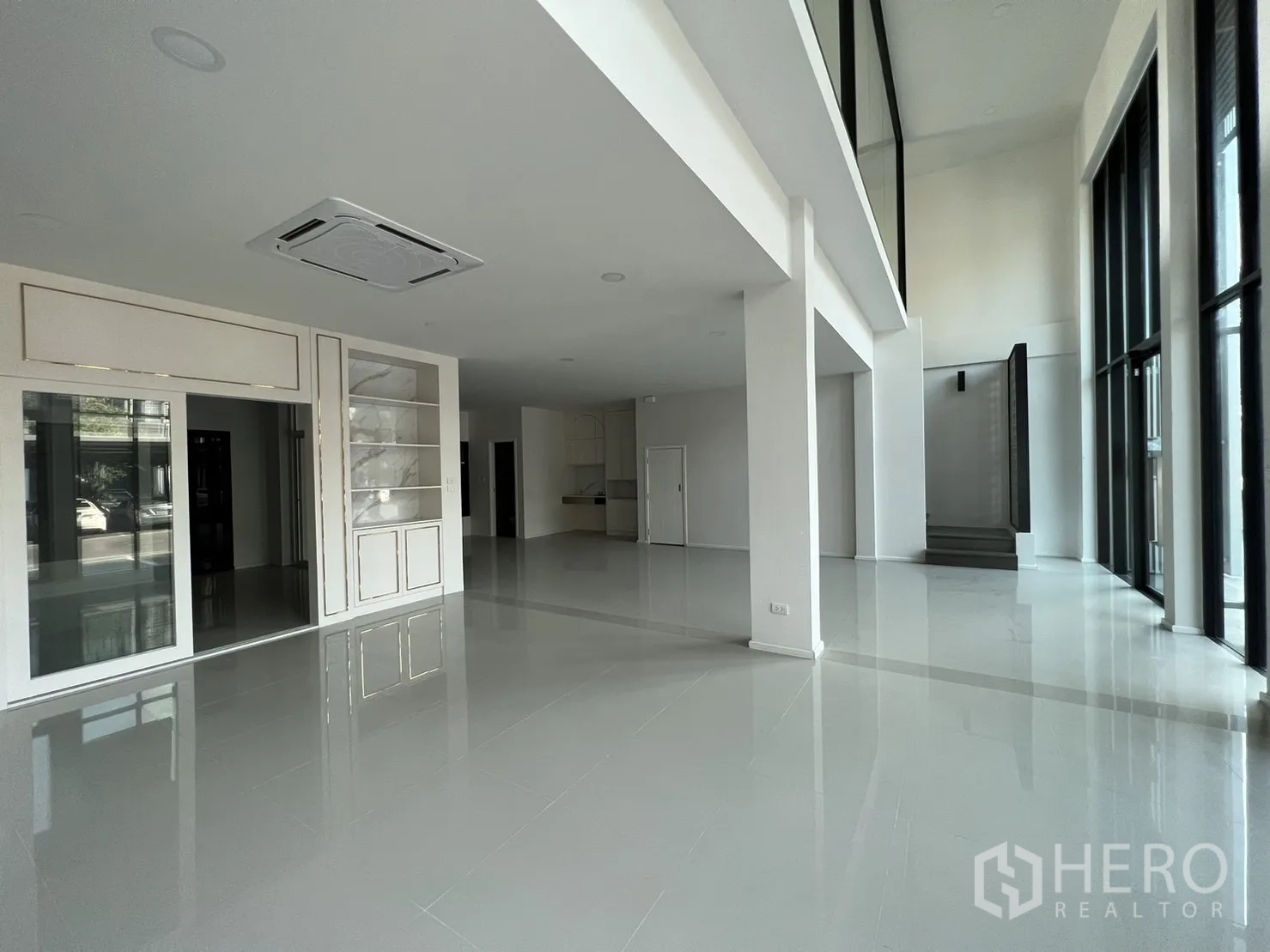 Home Office for rent in Bang Phli, Samut Prakan - Open‑plan ground floor with double‑height ceiling, polished floors and a side staircase.