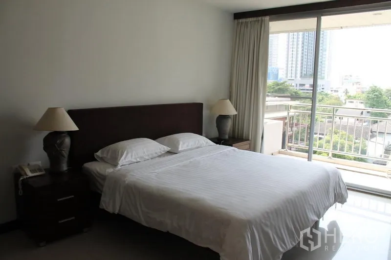 Apartment for rent in Bang Rak, Bangkok - Bedroom with king bed, bedside tables and balcony access with city view.