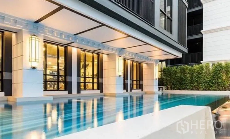 Condominium for rent or sale in Pathum Wan, Bangkok - Condominium outdoor swimming pool beside a stylish facade with warm lighting.