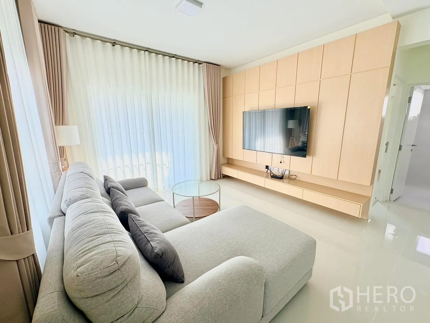 บ้าน for rent in Bang Phli, Samut Prakan - ห้องนั่งเล่นโซฟา L หันเข้าทีวี ม่านโปร่ง และโต๊ะกลางกระจกทรงกลม