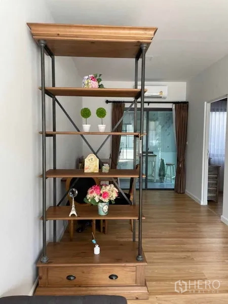 Townhouse for rent in Samut Prakan - Open-plan view with freestanding wooden shelf divider and sliding glass door to the kitchen.