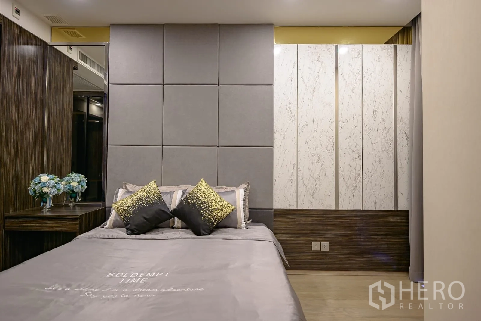 Condominium for rent in Watthana, Bangkok - Bed with padded headboard and marble-pattern wardrobe panels.
