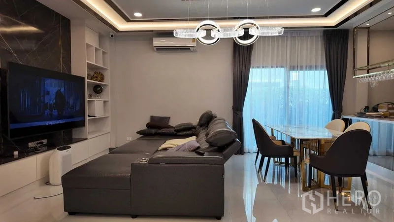 บ้าน ให้เช่าหรือขายในBang Na, Bangkok - ห้องนั่งเล่นครอบครัว โซฟาหนัง โคมไฟวงแหวน และประตูกระจกบานเลื่อน