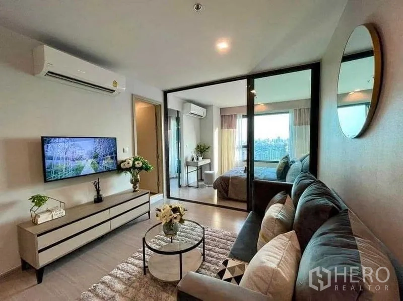 Condominium for rent in Chatuchak, Bangkok - Living area facing bedroom and balcony, wood flooring and soft ambient lighting.