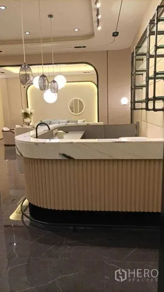 Retail Space for rent - Curved marble-top reception counter with hanging lights and display shelving.