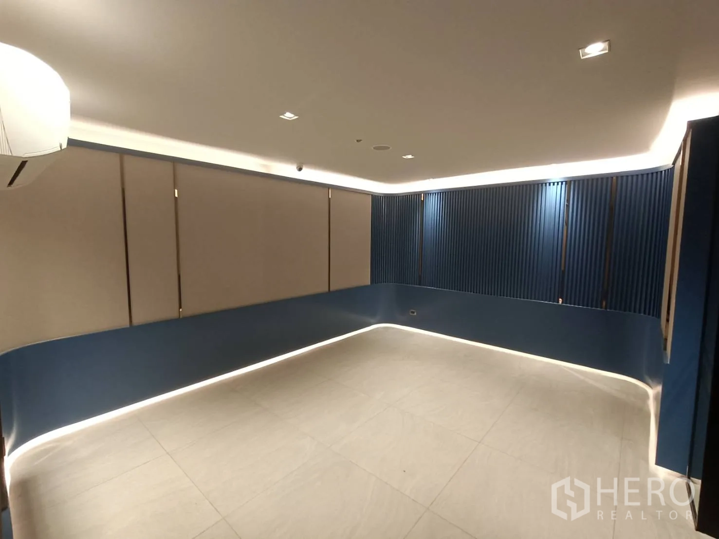 带办公室的家 出租或出售在Phra Khanong, Bangkok - 宽敞工作室，蓝色墙板搭配踢脚LED灯带，氛围柔和。