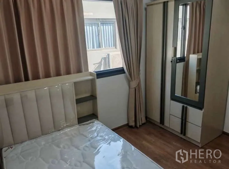 Townhouse for rent in Bang Phli, Samut Prakan - Secondary bedroom with single bed, mirrored wardrobe, beige curtains and wood flooring.