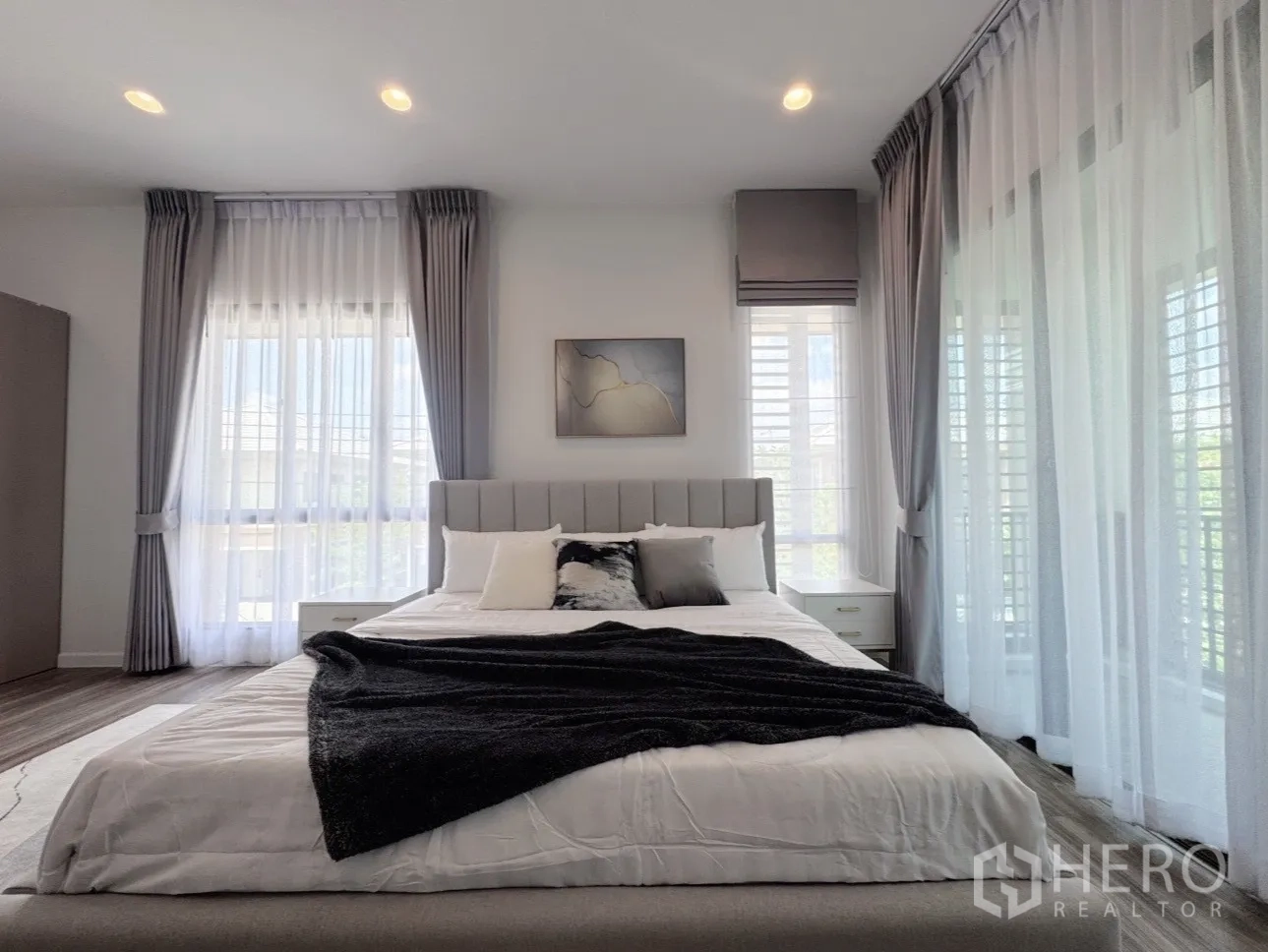 Detached House for rent or sale in Bang Kapi, Bangkok - Master bedroom close-up of upholstered bed, soft grey tones and sheer curtains.