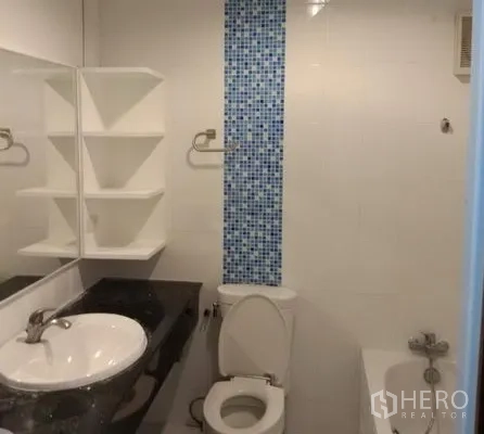 Apartment for rent in Pathum Wan, Bangkok - Clean bathroom with vanity sink, toilet, bathtub and blue mosaic accent tile.