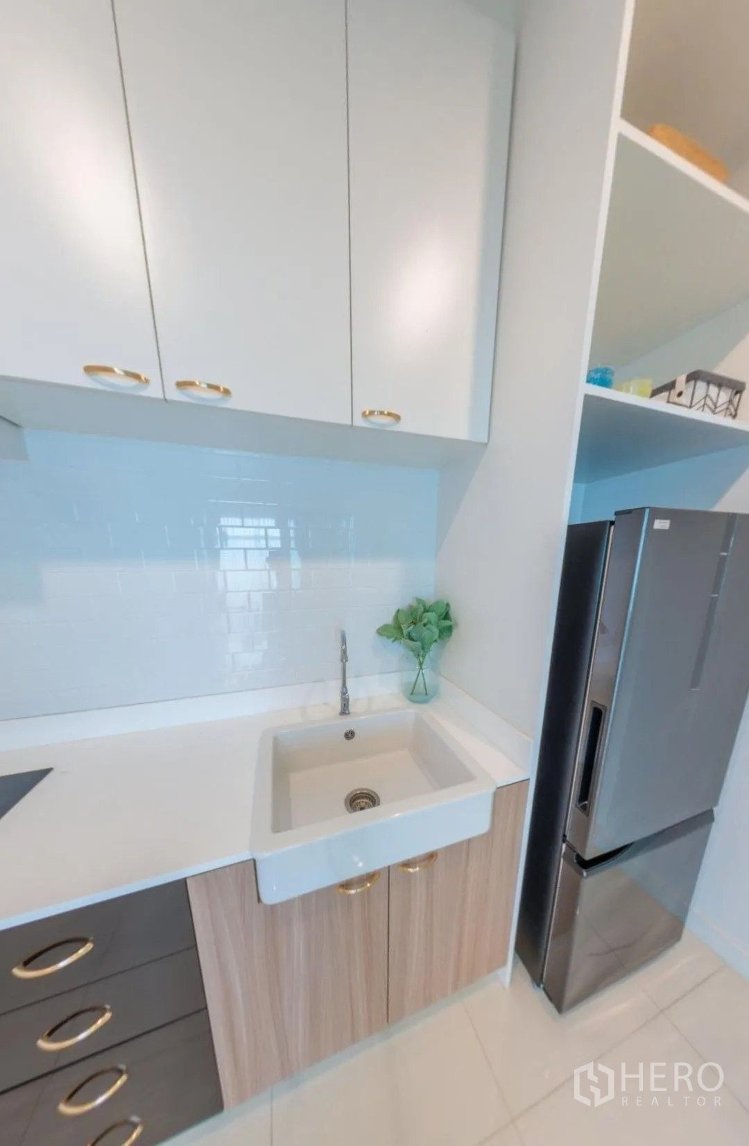 Detached House for rent in Lam Luk Ka, Pathum Thani - Compact kitchen with white cabinets, deep sink, tiled backsplash, and fridge.