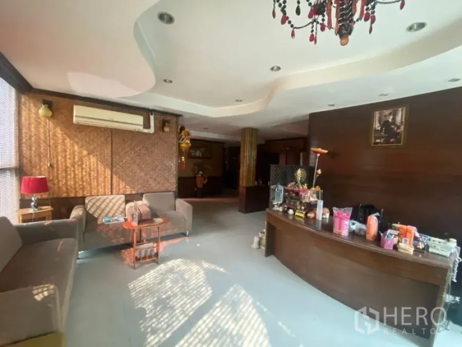 Office Space for rent in Khlong Toei, Bangkok - Reception area of Phra Khanong office with curved wooden desk, sofas and chandelier.