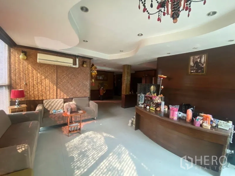 Office Space for rent in Khlong Toei, Bangkok - Reception area of Phra Khanong office with curved wooden desk, sofas and chandelier.