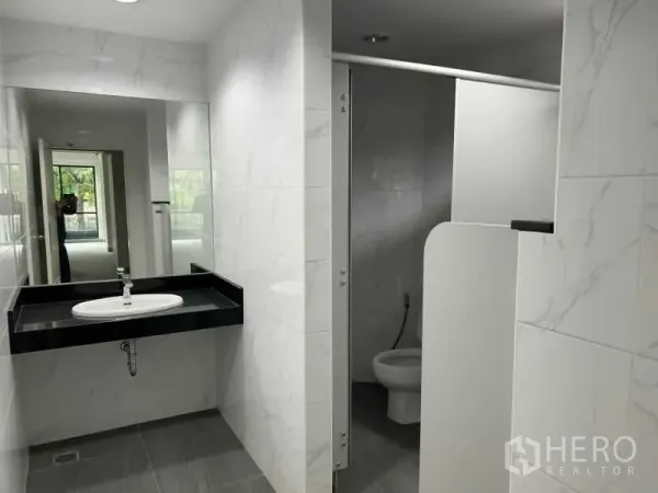 Office Space for rent in Bang Rak, Bangkok - Modern tiled restroom with large mirror, black countertop sink and a toilet cubicle.