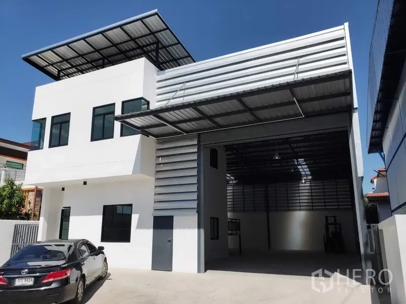 工厂 出租在Lam Luk Ka, Pathum Thani - 工厂正面带有遮雨装卸棚和宽敞车道停车区。