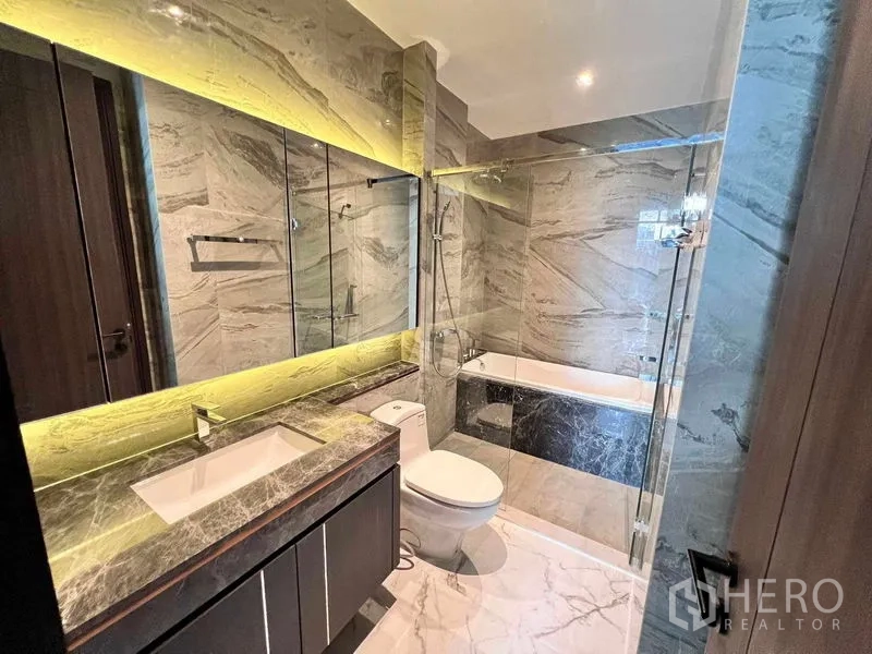 Condominium for rent in Watthana, Bangkok - Luxury bathroom with marble walls, backlit mirror, glass shower and bathtub.