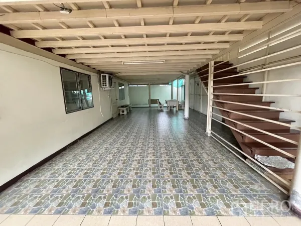 Warehouse for rent in Lat Phrao, Bangkok - Long ground-floor workspace with patterned tiles and metal staircase.