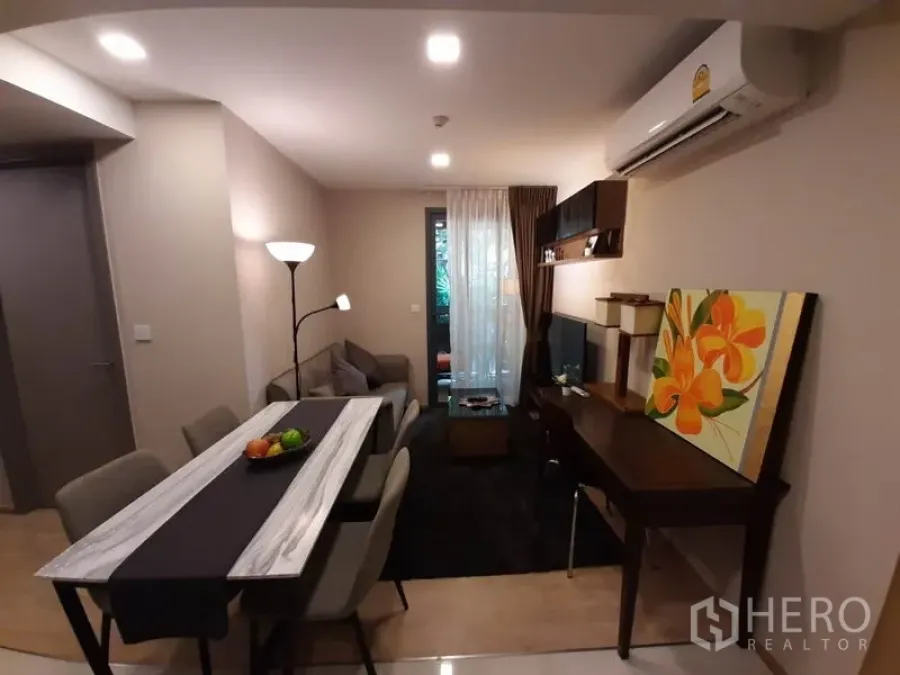 公寓 出租或出售在Watthana, Bangkok - 开放式客厅，配餐桌、电视墙、书桌及通往阳台的玻璃门，Ekkamai 公寓。