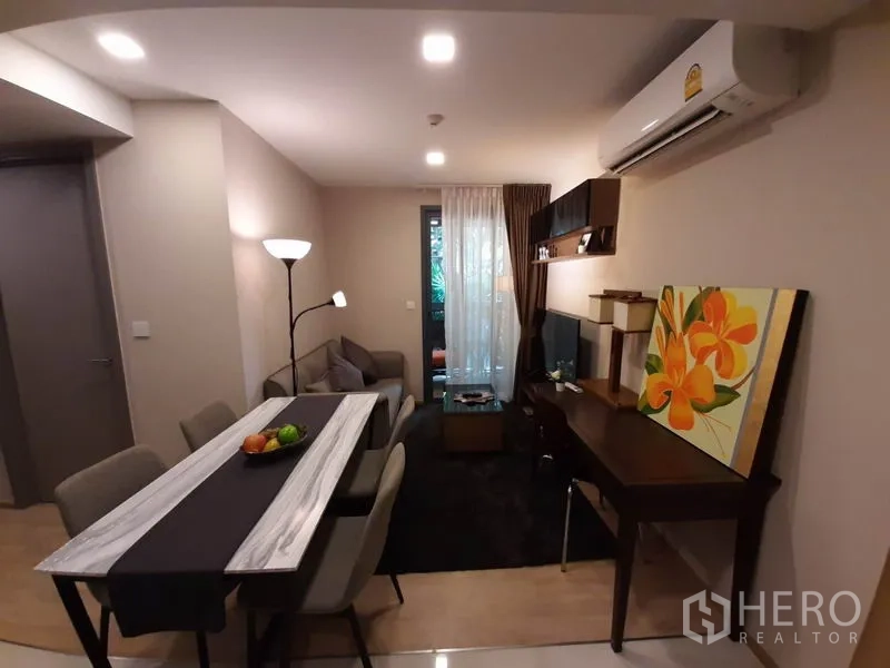 公寓 出租或出售在Watthana, Bangkok - 开放式客厅，配餐桌、电视墙、书桌及通往阳台的玻璃门，Ekkamai 公寓。