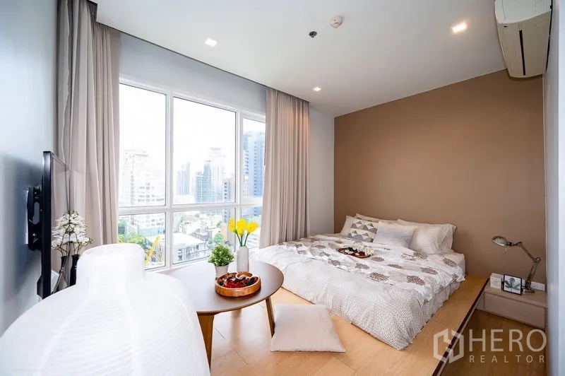 公寓 出租或出售在Watthana, Bangkok - 转角卧室设大面积窗户与暖色系背景墙，可观城市景
