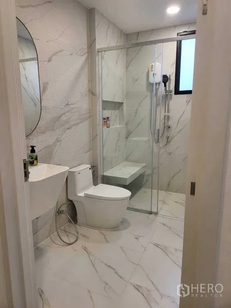 Detached House for rent in Saphan Sung, Bangkok - Clean marble-pattern bathroom with glass shower and built-in bench.