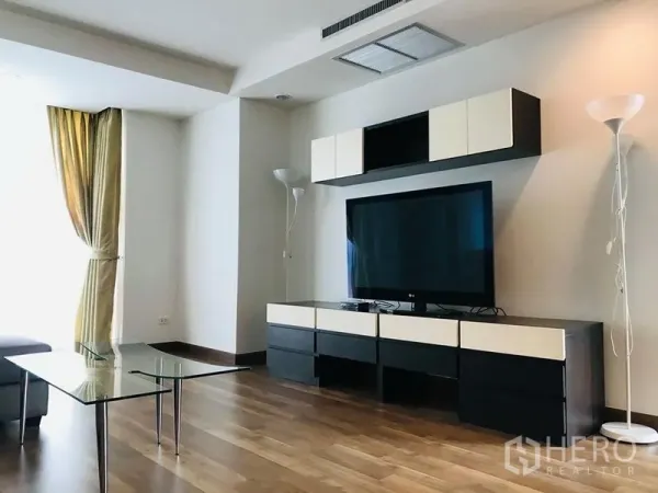 公寓 出租在Pathum Wan, Bangkok - 明亮客厅，木地板，大尺寸电视与现代电视柜，落地灯。