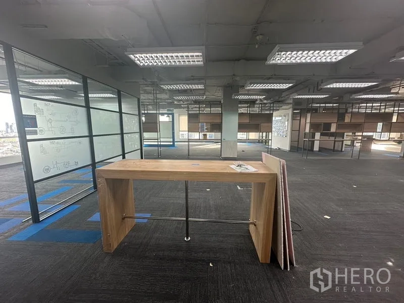 办公空间 出租在Bang Rak, Bangkok - 宽敞办公室内的木质站立桌，地毯砖与城市景观。