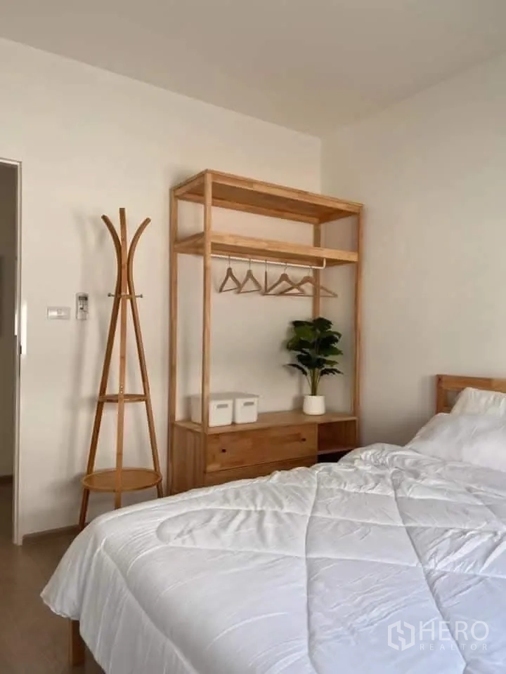Townhouse for rent in Bang Phli, Samut Prakan - Bright bedroom with wooden open wardrobe, coat rack, and white bedding.