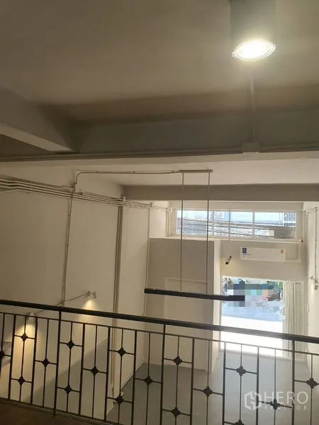 Shophouse for rent in Phra Khanong, Bangkok - View from mezzanine across railing to high-ceiling room and front glazing.