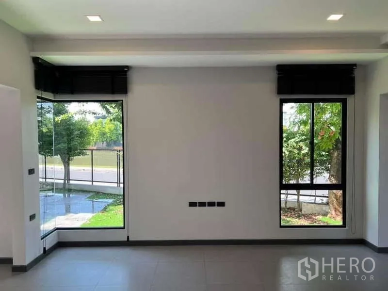 独立式住宅 出租或出售在Bang Phli, Samut Prakan - 落地转角窗特写，可见街景与树荫。