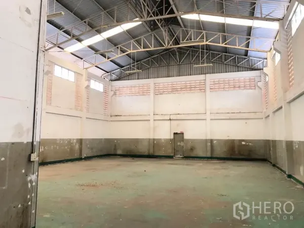 Factory for rent in Pathum Thani - Open production space with tall walls, ventilation windows and concrete floor beneath a metal roof.