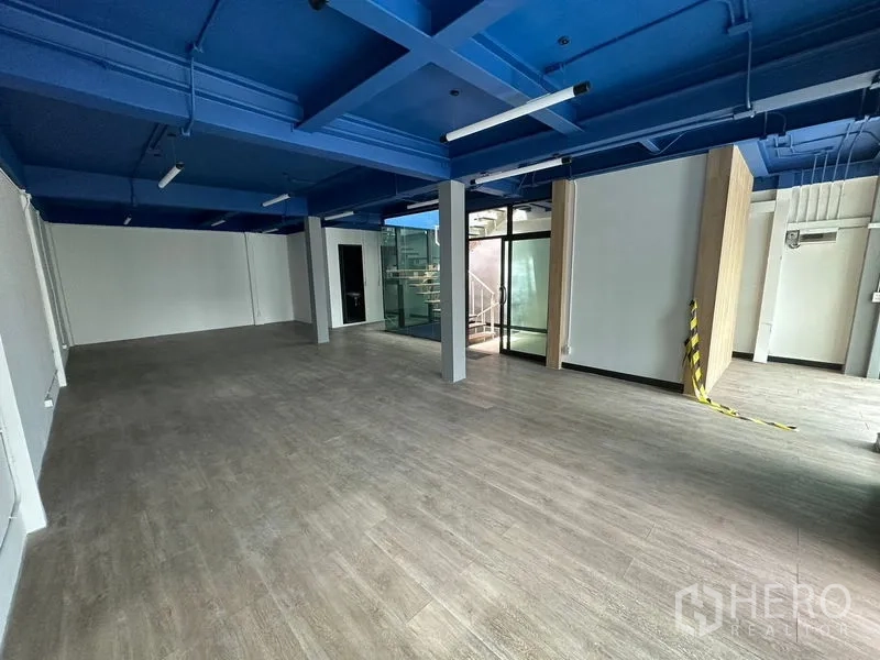办公空间 出租在Watthana, Bangkok - 宽敞办公楼层，立柱分区，玻璃入口与外露蓝色网格天花。