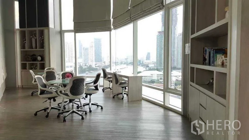 Condominium for rent in Bang Kho Laem, Bangkok - Co-working lounge with round tables, bookshelves, and river views.