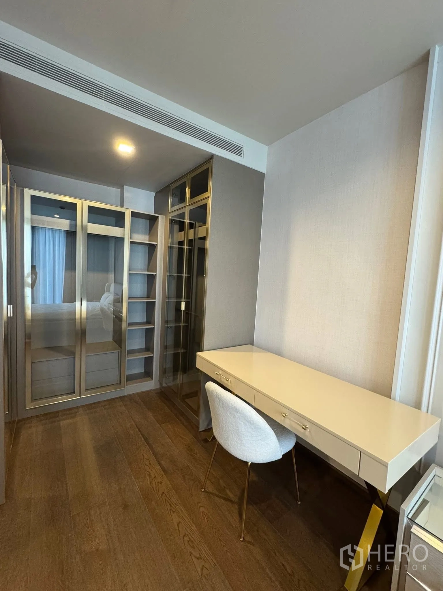 Condominium for rent in Khlong Toei, Bangkok - Study area with long built-in desk and gold-accent wardrobe.