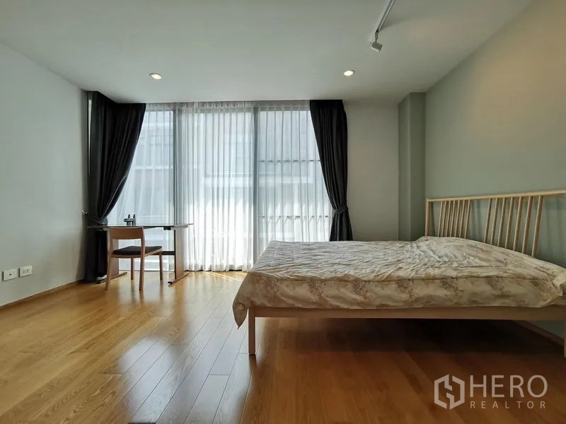 Townhouse for sale - Bright bedroom with floor-to-ceiling sheer curtains and tall windows.