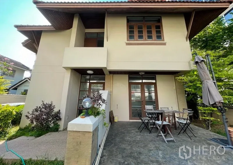 บ้าน ให้เช่าในKhlong Toei, Bangkok - บ้านเดี่ยวสองชั้นด้านนอก มีเฉลียงและชุดโต๊ะเก้าอี้กลางแจ้ง พร้อมแนวไม้พุ่ม