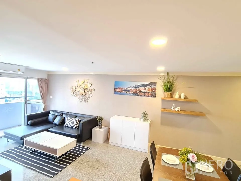 คอนโด for rent in Khlong Toei, Bangkok - ห้องนั่งเล่นสว่าง มีโซฟา ชั้นวาง และงานศิลป์ติดผนังใกล้ประตูกระจก.