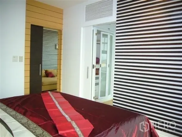 Condominium for rent in Khlong San, Bangkok - Bedroom with built-in storage, striped accent wall and glass door to bath.