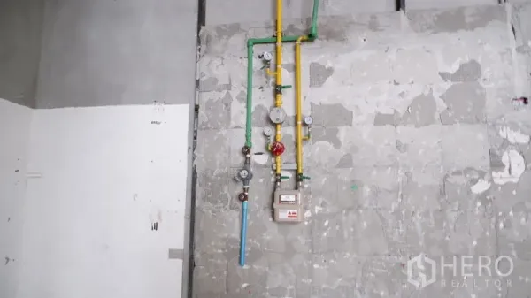 Retail Space for rent in Watthana, Bangkok - Close-up of installed gas and water meters with colored pipes on an unfinished wall.
